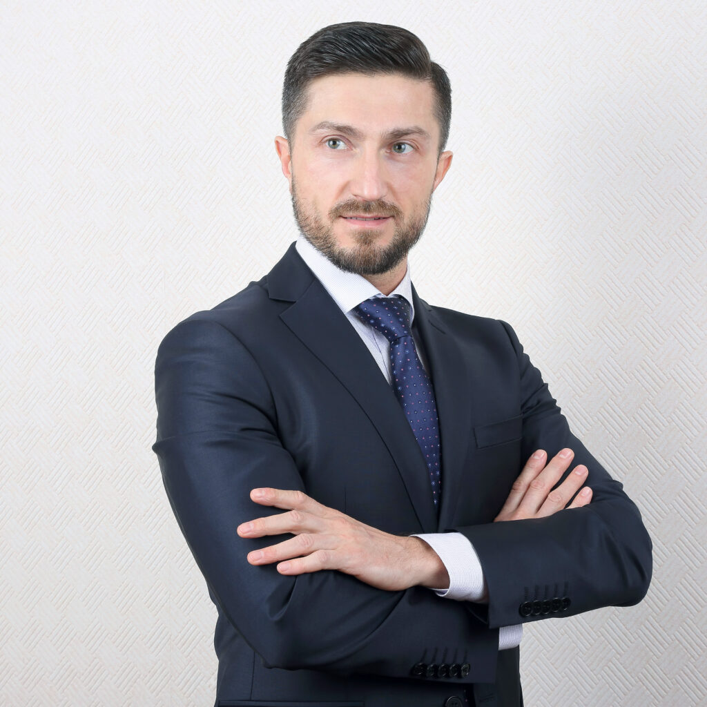 A man in a suit and tie stands confidently with his arms crossed, exuding professionalism and authority.